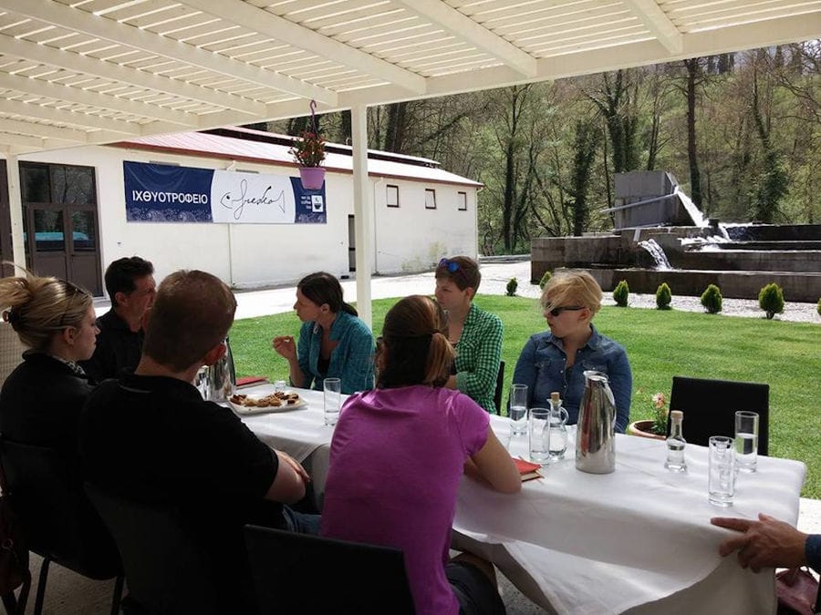a group of tourists sitting on a long table under awning outdoor at 'Fresko'